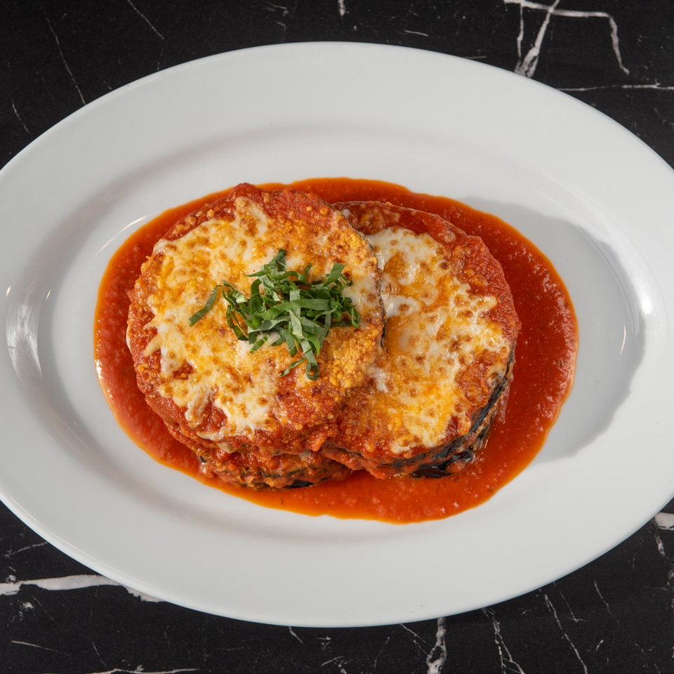 Lexie's Bistro's eggplant parmesan, topped with melted cheese, tomato sauce, and fresh basil.